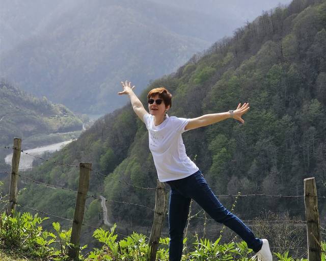 A guest with arms spread wide above a valley in the Adjara mountains