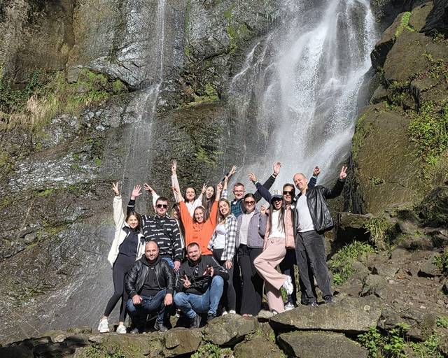 A tall waterfall with tour guests at its foot
