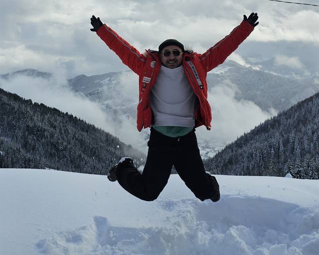 Jumping in the snow with mountains behind