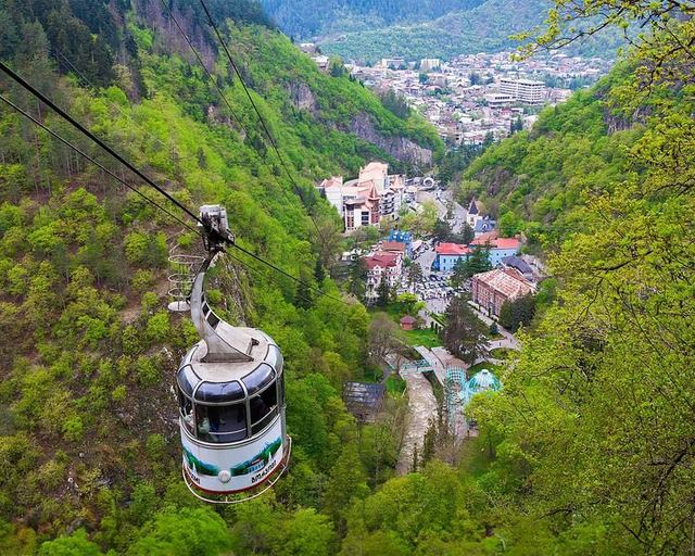 A cable car cabin above the city in a green gorge