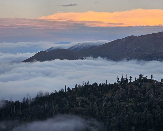 Clouds in the valley and a sunset sky over the mountains