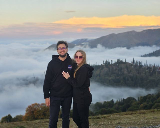 A couple on a slope above a sea of clouds