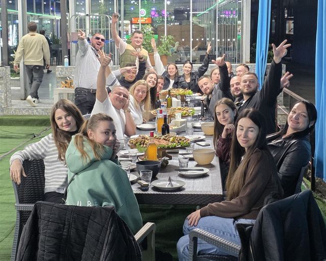 Guests at a shared table waving at the camera