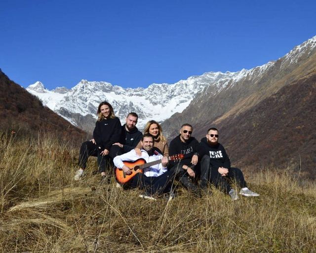A group with a guitar on a slope in front of a glacier