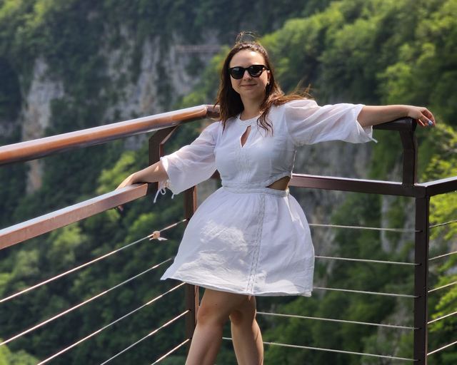 A guest in a white dress on a viewpoint above a gorge