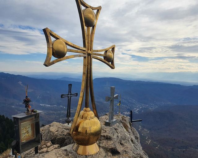 A golden cross on a summit above the valleys of Racha