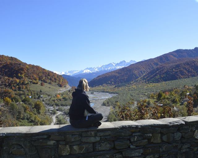 A guest sitting on a stone wall above a valley