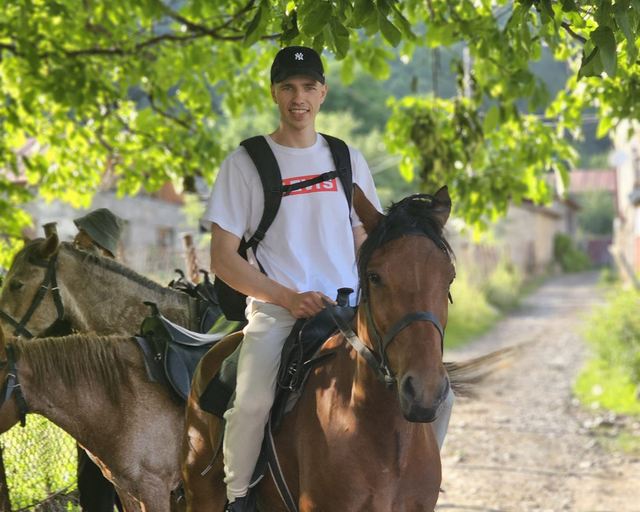 A rider on a trail through the greenery of a Svan village