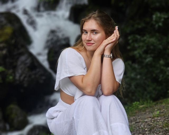 A woman by a mountain waterfall