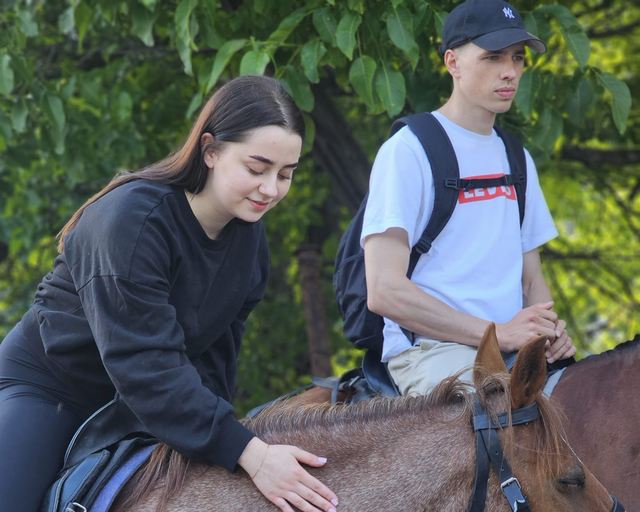 Two guests with a horse on a forest trail